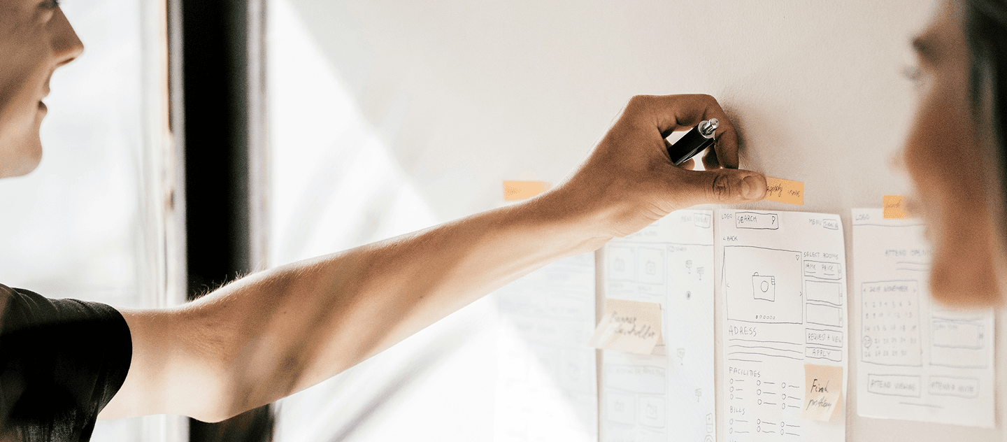 Professionnel plaçant une note sur un mur d'idées lors d’une séance de travail collaboratif
